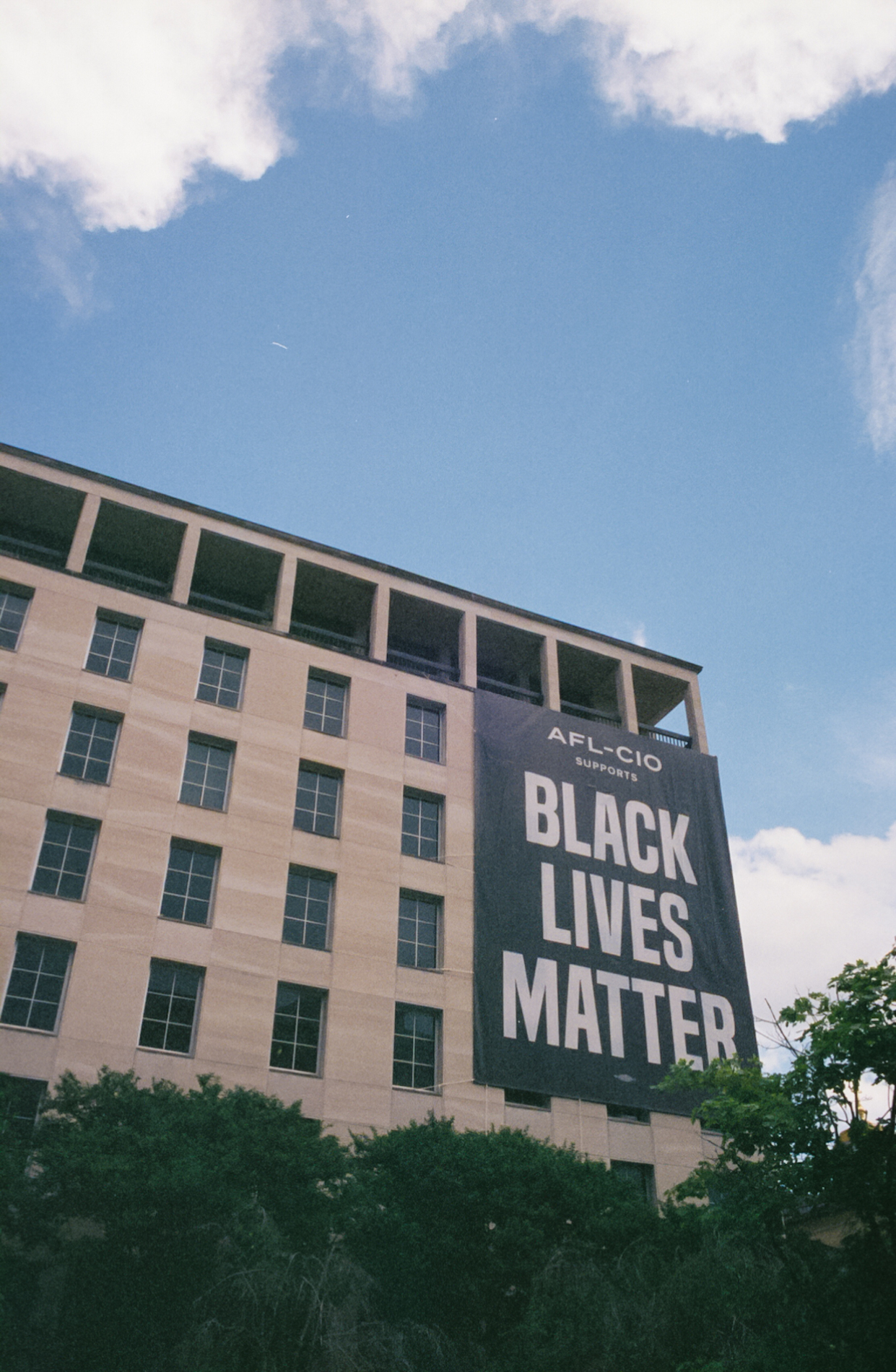 A giant banner saying Black Lives Matter covers multiple floors of a building